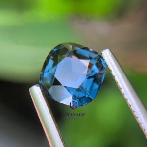 1.16 ct natural unheated Ceylon steel blue spinel held in tweezers showing deep grayish-blue color